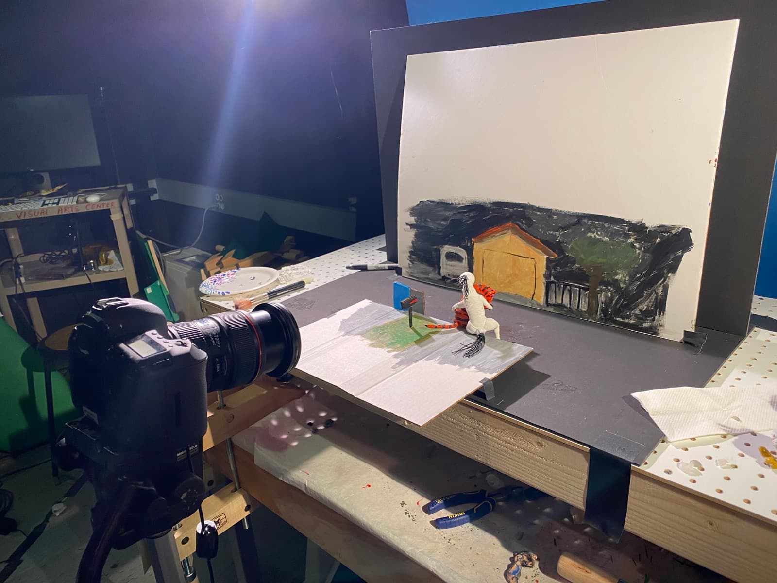 Behind the scenes: a DSLR on a rig aimed at the miniature set — handmade puppets on a hand-painted backdrop in the Visual Arts Center studio.