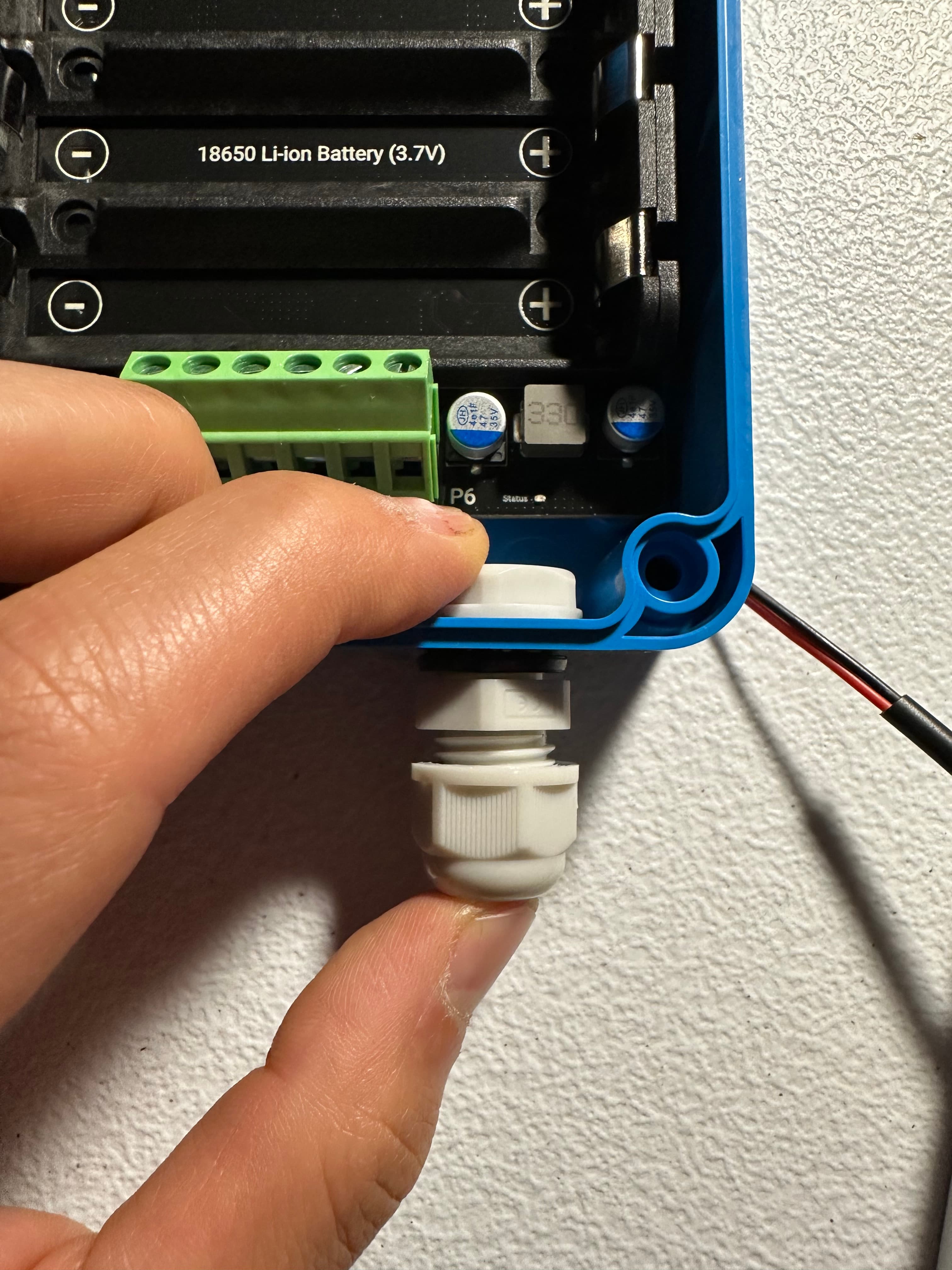 Threading a waterproof cable gland into the enclosure wall.