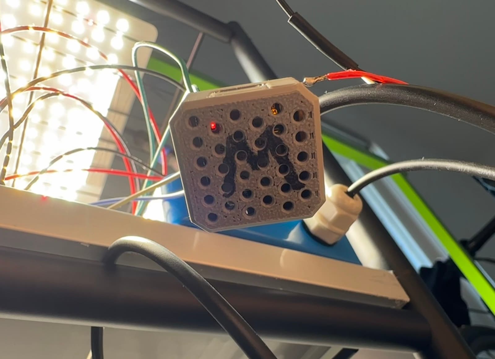 The printed 'M' pod — Mario's sensor grille, glanded and hung under the grow light.