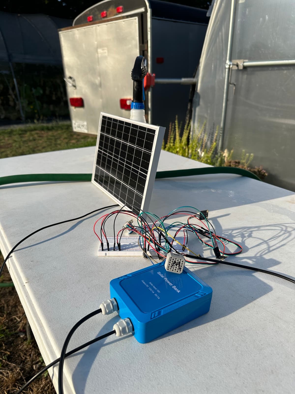 Deployed: panel up, node sealed, sensor leads fanned across the farm work table.