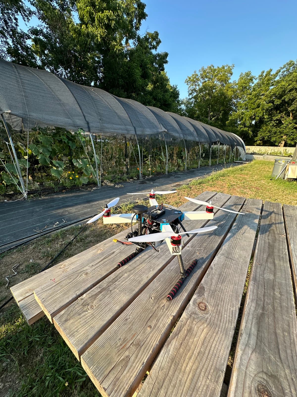 The X500 on a picnic table by the shade house — the farm-flyover layer arrives.